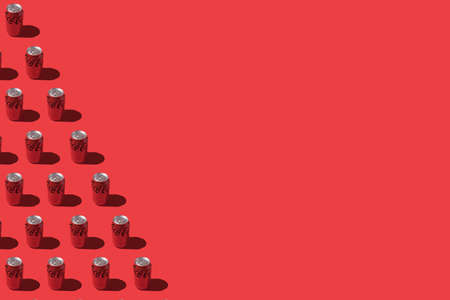 Madrid, Spain - November 26, 2021: Coca cola cans pattern with hard shadow, on the left side, on red background.のeditorial素材
