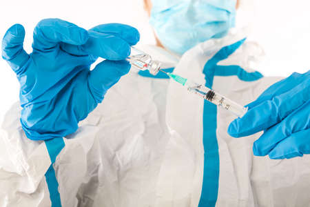Medical nurse in PPE and latex gloves carrying a syringe with a covid-19 vaccine. Coronavirus, pandemic and health concept.の写真素材