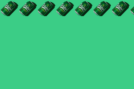 Pattern of green Heineken Dutch beer cans with hard shadow, on top, on white background. Alcohol,...