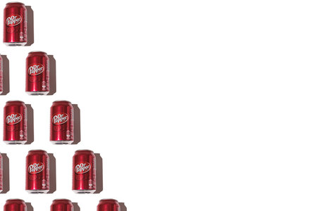 Dr. Pepper cans pattern on the left side, with hard shadow on white background.
