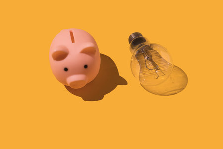 Piggy bank and light bulb on yellow background. Concept of electricity, rising prices,...