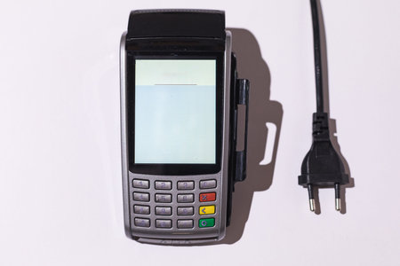 Dataphone to pay with a credit card next to an electric cable on a white background. Concept of...