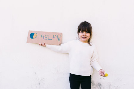 Anti-war activist little girl holding a sign that reads: 'HELP' with the colors of the Ukrainian...
