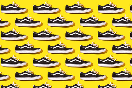 Madrid, Spain - June 21, 2022: Pattern of Vans Old Skool Retro black and white sneakers on yellow background. Skate, surf, fashion, sneaker, modern and retro concept.のeditorial素材