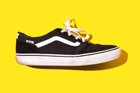 Madrid, Spain - June 21, 2022: Vans Old Skool Retro black and white sneaker on yellow background. Concept of skateboarding, surfing, fashion, sneakers, modern and retro.のeditorial素材