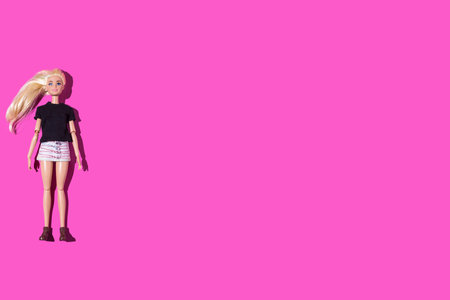 Mattel Barbie doll with black t-shirt and skirt, on the left side, on pink background. Doll, childhood, toy, mattel and game concept.のeditorial素材