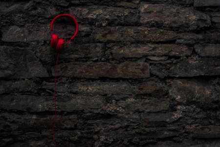 Red headphones hanging on old stone wall.の写真素材