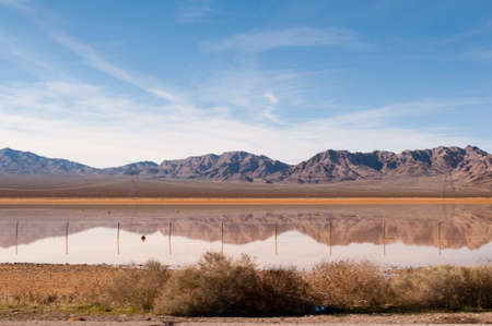 Flooding left a lake in the middle of a desert lowland which is reflecting the mountains in the background.の写真素材