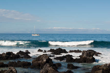 This boat has chosen the perfect day to be out on the ocean with the beautiful wave in the foreground.の写真素材