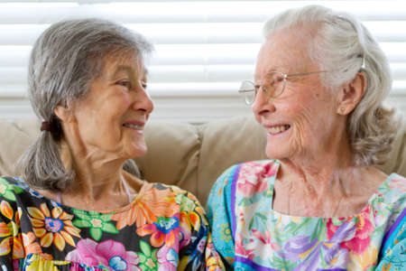 Two Elderly Friends Smiling at Each Otherの写真素材