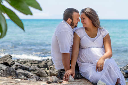 Young couple sitting on beach lovingly gazing into eathotherの写真素材