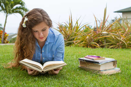 Pretty teen girl studying her school books outside in a tropical setting の写真素材