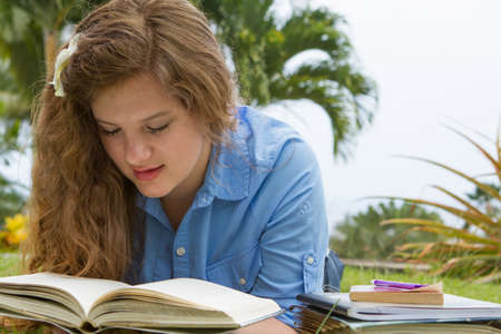 Pretty teen girl studying her school books outside in a tropical setting の写真素材
