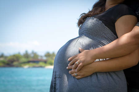 Married couple with hands on pregnant belly of their unborn child の写真素材