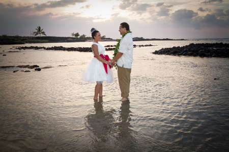Newlywed couple standing in the warm, shallow waters of Hawaii の写真素材