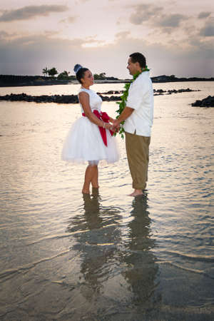 Newlywed couple standing in the warm, shallow waters of Hawaii の写真素材
