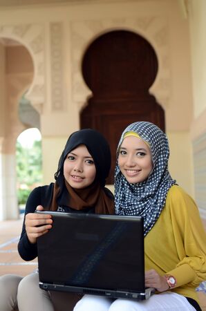 Young asian muslim woman in head scarf smile with laptopの写真素材