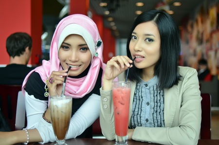 Close-up portrait of beautiful young Asian Muslim woman at cafe with lovely smilesの写真素材