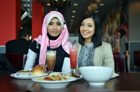 Close-up portrait of beautiful young Asian Muslim woman at cafe with lovely smilesの写真素材