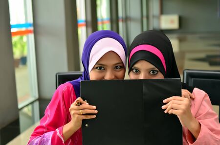 Two Asian muslim hide face and happyの写真素材