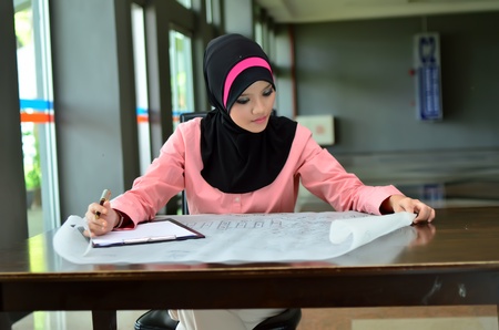 young pretty Asian muslim business woman in head scarf busy at workの写真素材