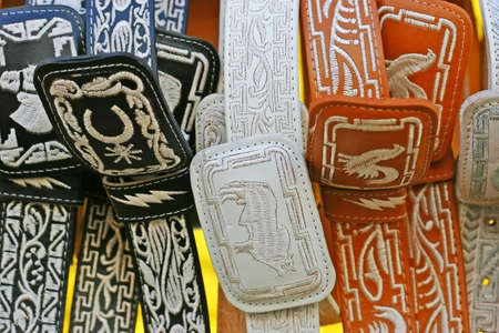 hanging black, orange and white cowboy belts の写真素材