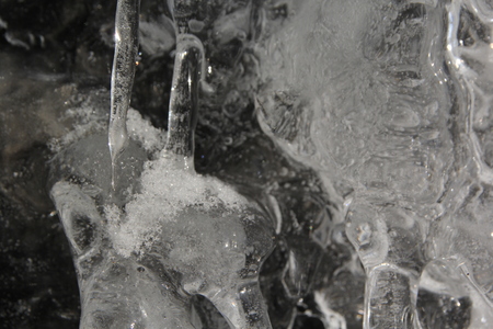 Icicles hanging on a ledge with rocky bacground after thawingの写真素材