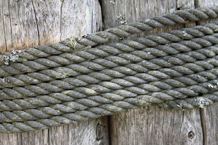 wooden fencing post standing on a sandy beach with rope