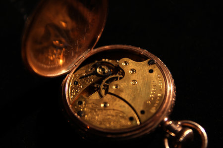 Antique pocket watch on black background and open latch showing the mechanismの写真素材