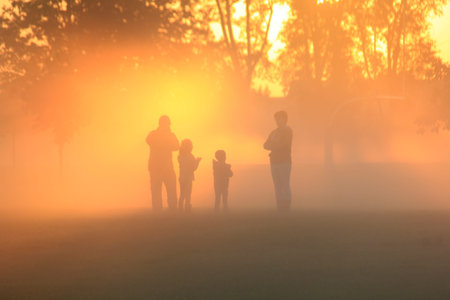 Family playing in the early morning fog at sunriseの写真素材