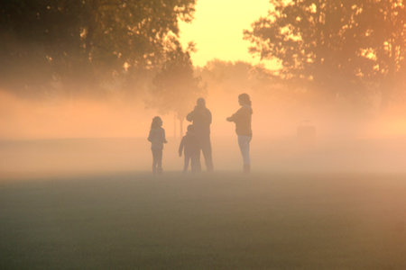 Family playing in the early morning fog at sunriseの写真素材