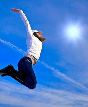 The girl highly jumps in the  blue skyの写真素材