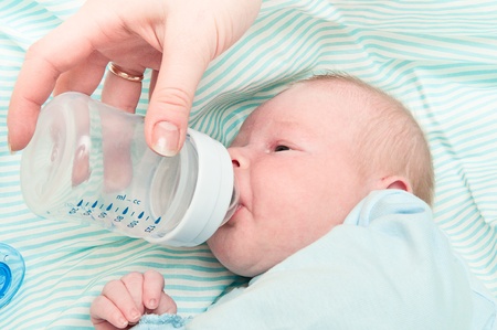newborn baby is eating from a bottleの写真素材
