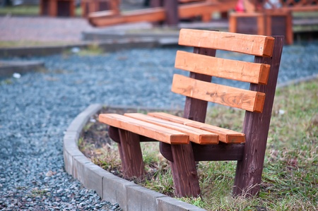 wooden bench in a park on the sidewalkの写真素材
