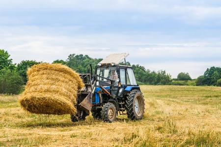 tractor removes the hay in the fieldのeditorial素材
