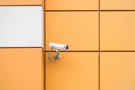 video surveillance camera hanging on the wall of a buildingの写真素材