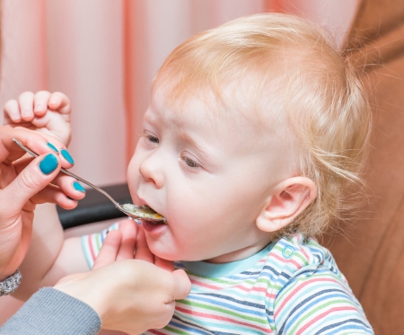 mother feeds her baby cereal from a spoonの写真素材
