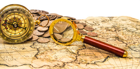 compass and magnifying glass gold color on the old map with coins