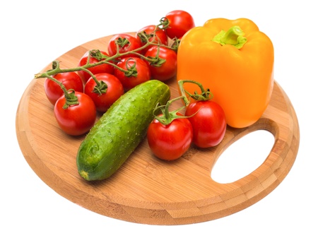 cucumber pepper and tomatoes on a cutting boardの写真素材