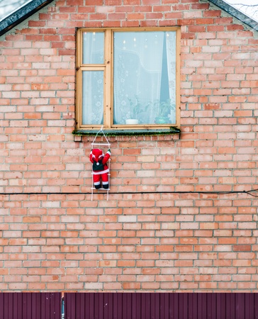 Santa Claus climbing out of the window on the stairsの写真素材