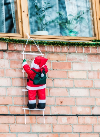 Santa Claus climbing out of the window on the stairsの写真素材