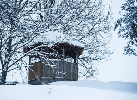 wooden gazebo in the winter under the snow on the hillの写真素材