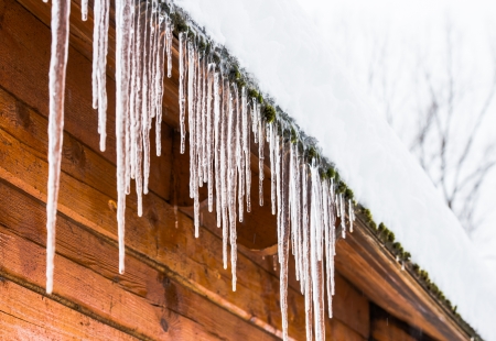 roof of the house with snow and icicles hangingの写真素材