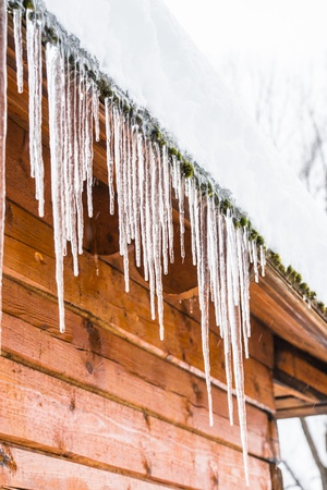 roof of the house with snow and icicles hangingの写真素材