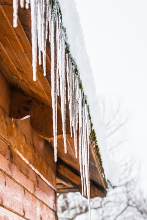 roof of the house with snow and icicles hangingの写真素材