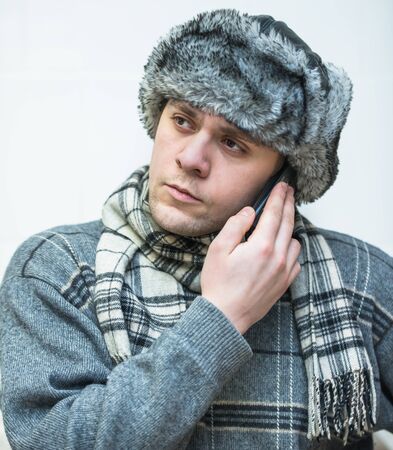 a young man with a phone in a winter capの写真素材