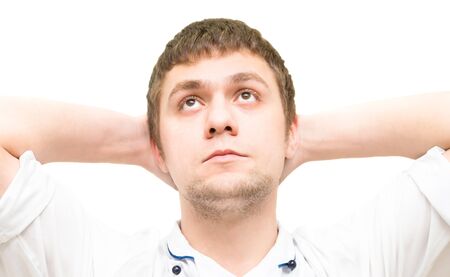 young guy sits his hands raised over his headの写真素材