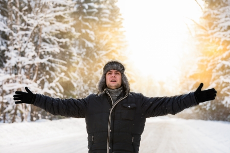 man spread his hands in the winter in the sunの写真素材