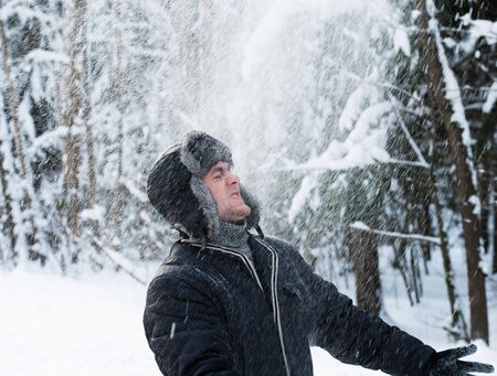 A young man throws up snow in the forestの写真素材