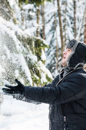 A young man throws up snow in the forestの写真素材